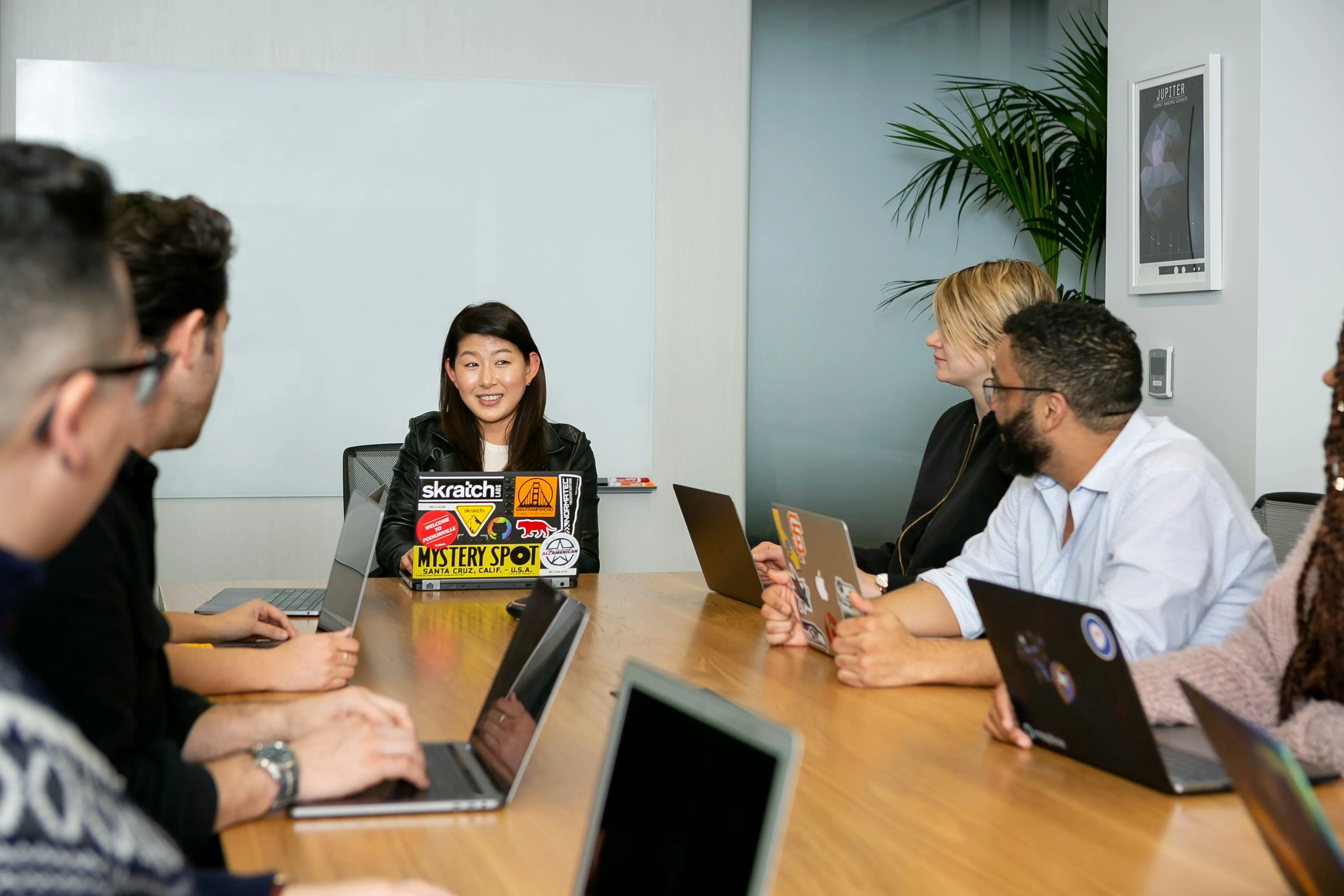 Five people around a conference table with laptops open during a software demo